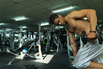 Fototapeta na wymiar Fitness man in training showing exercises with dumbbells in gym