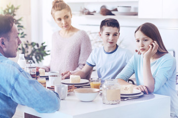 Upset young lady getting emotional during family breakfast