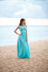 Fototapeta na wymiar Beautiful young girl in a light blue long dress on the beach 