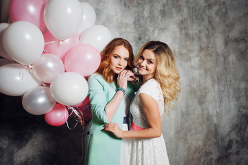 Blonde and redhead. Two young charming girlfriends at the party. Happy and cheerful girl with balloons.