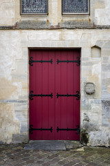 Fototapeta na wymiar Red wooden door in an ancient stone wall