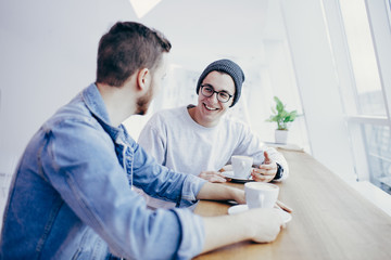 Men are sitting in front of the table near window