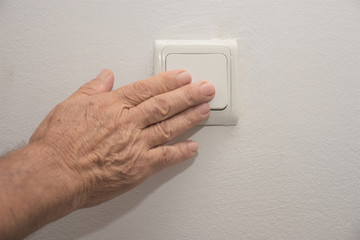an old man turns of a light switch
