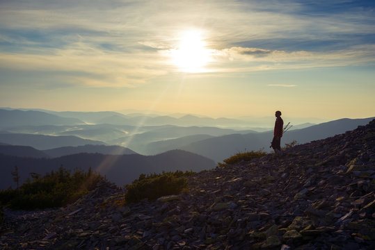 Traveler goes down along mountain slope during sunset