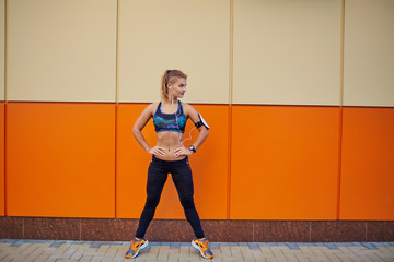 A sports young girl stands after training on a background of an orange wall.