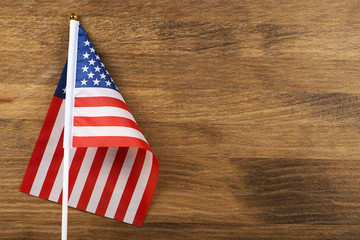Fototapeta na wymiar Studio shot of small bright flag of USA lying on wooden background. Copy space.
