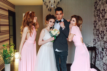 Cheerful young newlyweds along with cute bridesmaids