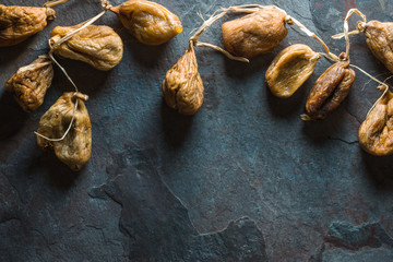 Dried beige figs with a string on a gray stone free space