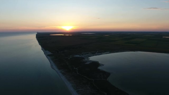 Wonderful view of a wild prolong and narrow island, with a big white sun over it in the Black Sea  from the bird`s eye perspective in the evening in summer. The seascape looks magic and marvelous