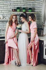 Fototapeta na wymiar Stylish bridesmaids in pink dresses along with the bride. Young slender bride with bridesmaids at home.