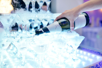 Beautiful wedding couple is pouring champagne indoors