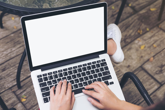 Mockup image of a woman sitting , using and typing on laptop with blank white screen on thigh at outdoor background