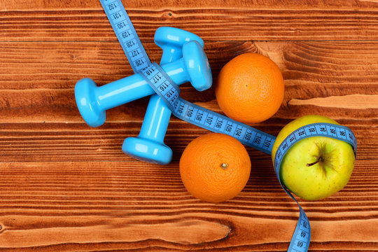 fitness body concept, dumbbells weight with measuring tape, fruit