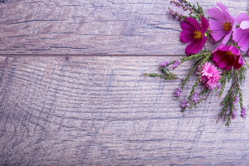 A bouquet of pink and purple flowers cosmea or cosmos with ribbon on rustic wooden boards. Copy...