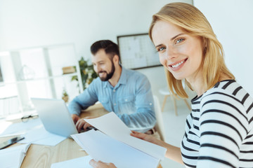 Obraz premium Cheerful woman holding documents and smiling at camera