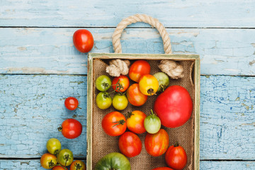 Set of different sorts of ripe tomatoes in the wooden tray