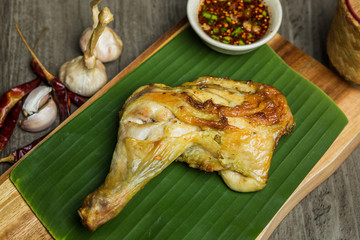 Roast Chicken drumstick serve on wooden plate with Thai style sauce and sticky rice