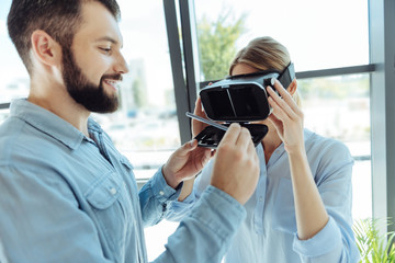 Pleasant man adjusting a VR headset of his colleague