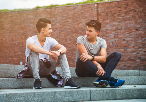 Two friends casual wear sitting on stairs in town and talking, best friend - Powered by Adobe