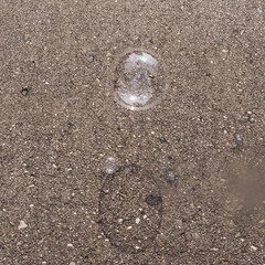 Two transparent soap bubbles with shadows on grey asphalt background top view