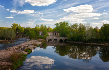 Summer landscape with a dam through the river and fishermen in a sunny day