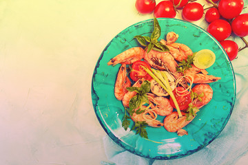 Bbq grilled shrimps on blue plate serving with cherry tomato, parsley, basil, leek and baked garlic. Barbecue seefood concept. Healthy diet food. Top view.