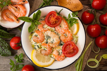 Overhead of dinner table. Seefood casserole with leek, cheese, grilled shrimps, serving with tomato cherry, parsley and basil. Ingredients around plate with seefood meal.
