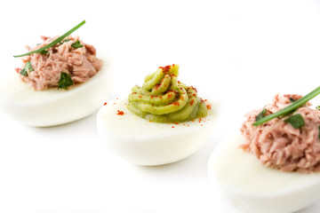 Variety of stuffed eggs with avocado and tuna isolated on white background

