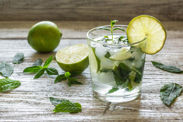 Mojito cocktail with lime and mint in highball glass on a white wooden background