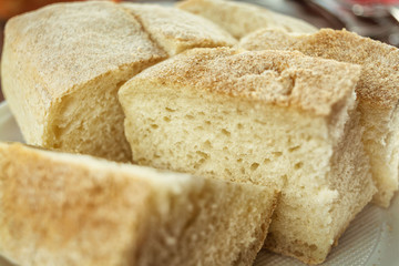 Fresh soft white bread with crust on a plate on a wooden table