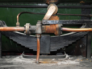 detail of pipes and leaf spring on an old green steam locomotive