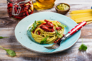 Homemade pasta spaghetti with pesto sauce and dried tomatoes. Copy space