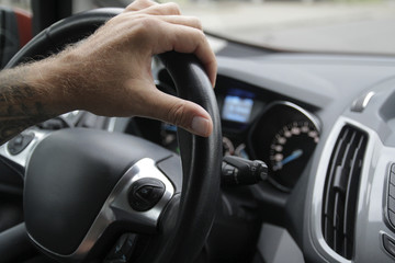 The man drives the car, turns the steering wheel and drives forward
