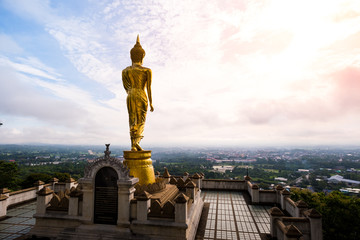 Golden Buddha statue standing on a mountain at Wat Phra That Khao Noi, Nan Province, Thailand with  wonderful sky