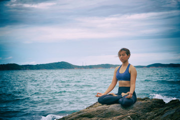 Fototapeta na wymiar Asian woman yoga and meditation on the sea beach.