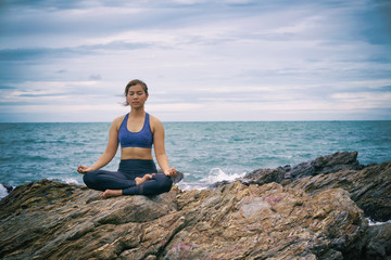 Naklejka na ściany i meble Asian woman yoga and meditation on the sea beach.