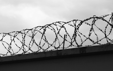 Concrete wall with barbed wire on fence