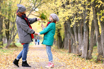 Mom and daughter on a walk in the autumn park