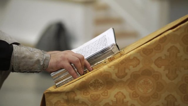 Priest in church praying with a book
