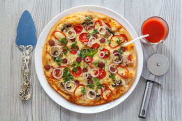 Fresh homemade pizza with tomatoes, salami, cheese and mushrooms on white plate