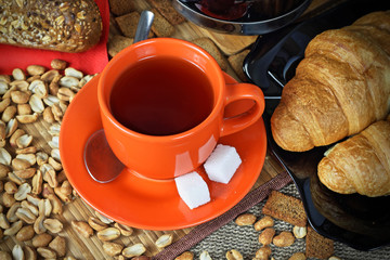 Orange cup of tea and croissants