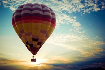 Fotobehang Ballon Kleurrijke heteluchtballon die op hemel vliegt bij zonsondergang. reis- en luchttransportconcept - vintage en retro filtereffectstijl