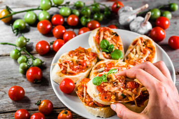 Hand eating appetizer or bruschetta, traditional italian food from plate
