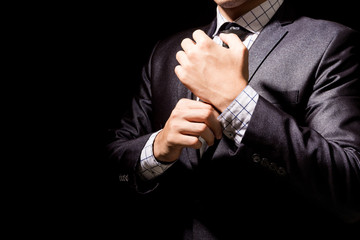 Businessman adjusting his suit on black background