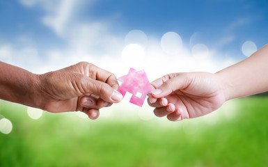 Hand of old women giving paper card house to young woman metaphor and concept for asset heritage of mother and daughter
