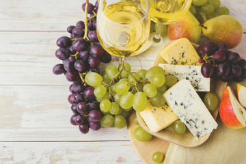 Cheese plate served with wine, fresh grapes and pears