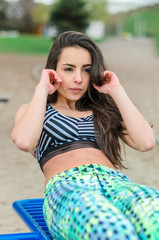 Girl beautiful brunette. Athletic body , pumped muscles. Bright colors , green ,pink . Spring , trees in bloom. She does exercises on the beach , running.