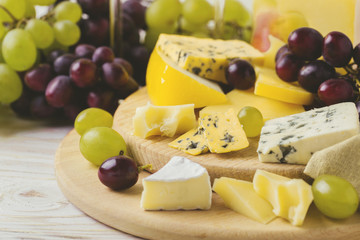 Cheese plate served with wine, fresh grapes and pears