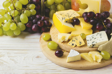 Cheese plate served with wine, fresh grapes and pears