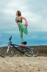 Fototapeta premium The girl the brunette plays sports on the seashore - on the beach.